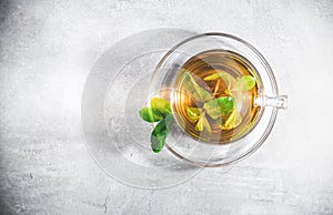 Mint tea leaves in a cup with on gray table. Topview, above. Glass teacup on saucer