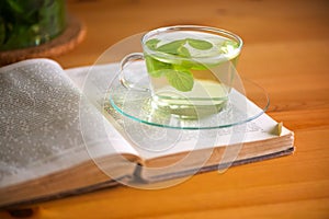 Mint tea in transparent glass tea cup on opened book.