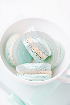 Mint or tiffany color macaron or macaroon dessert with vanilla cream in white cup. Copy space