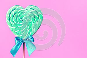 Mint and white spiral heart lollipop isolated on pink backgroun