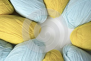 Mint and yellow acrylic yarn on a white background, lined up in a circle, with copyspace. Beautiful yarn for knitting baby clothes