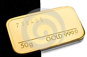 Minted gold bar weighing 50 grams on a black and white background. photo
