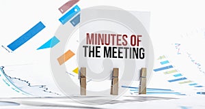 MINUTES OF THE MEETING text on paper sheet with chart, dice, spectacles, pen, laptop and blue and yellow push pin on wooden table