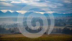 Mioritic landscaoe with tiny house and mountains in the background