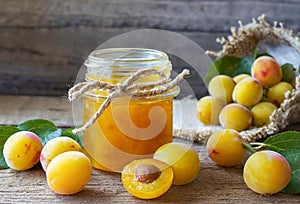 Mirabelle plums and jar of jam on a wooden table,