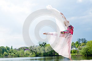 Miracle dancer: image of wonderfully dancing blond girl in light dress at water lake on lighting rays sunshine blue sky outdoors