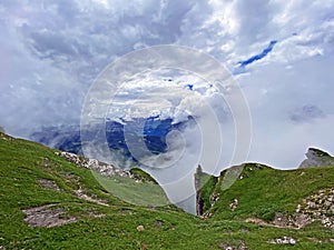 Miraculous low clouds and a mystical fog of the mountain range First and in the Schwyz Alps mountain massif, Oberiberg