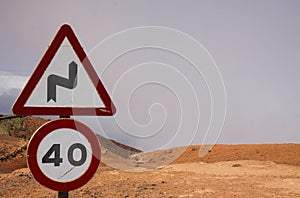 Mirador del Rio - Lanzarote:  Close up of Speed limit 40 sign and warning for curves signs above clouds on dry mountain Focus on