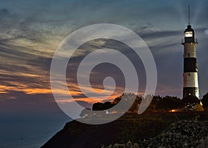Miraflores` famous historical lighthouse on the pacific coast of Lima in orange / golden sunset light photo