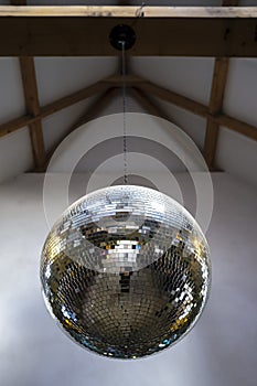 Mirror, brilliant, reflective disco ball hanging on a chain from the ceiling