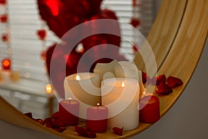 Mirror and burning candles in bathroom decorated for Valentine's day, closeup