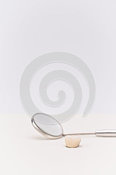 Mirror and ceramic dental crown on a white desk with space for text