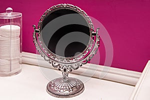 Mirror with chromed metal structure and bright pink painted wall