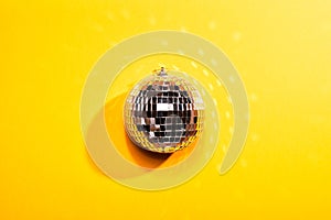 Mirror disco ball on yellow paper background.