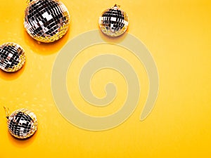 Mirror disco balls on yellow paper background.