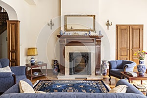 Mirror in gold frame above fireplace in sophisticated living room interior of english house. Real photo