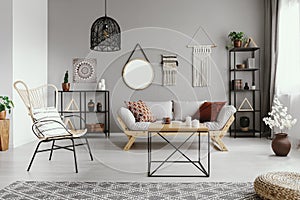 Mirror, macrame and graphic on the grey wall of warm ethno living room