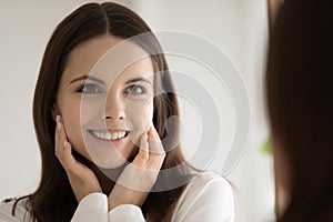 Mirror reflection head shot smiling woman touching healthy smooth skin