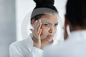 Stressed young african american woman worrying about first wrinkles.