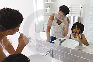 Mirror reflection of hispanic father and son brushing teeth together in bathroom