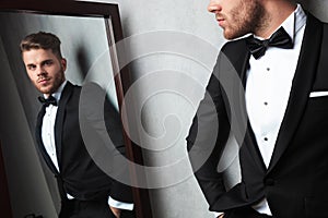 Mirror reflection of relaxed young man wearing a black tuxedo photo