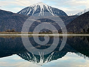 Mirror reflection of a snow-covered mountain in a lake with mountain water in Martigny, Switzerland