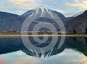 Mirror reflection of a snow-covered mountain in a lake with mountain water in Martigny, Switzerland