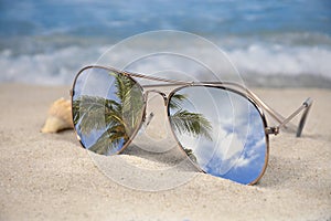 Mirror sunglasses in tropical beach sand