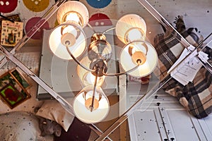 Mirrored ceiling in the bedroom. Chandelier with three lamps close-up. Interior of the living room is reflected in the ceiling