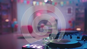 A mirrored disco ball casts multicolored reflections on a professional cd turntables. Close up of a DJ console against a