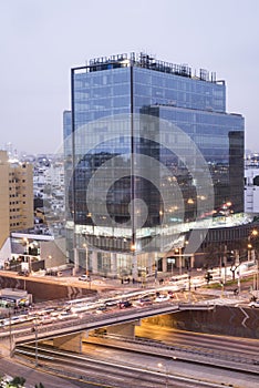 mirrored modern building of a corporation with a highway with a lot of traffic and the line of the metropolitan bus at night, oct