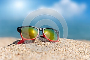 Mirrored sunglasses close up on the beach sand