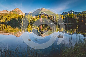 Mirroring at Strbske lake, Slovakia. High Tatras in background. Autumn forest reflected in water