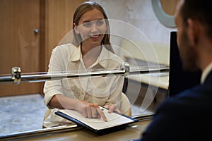 Mirthful lady approaching the receptionist and smiling