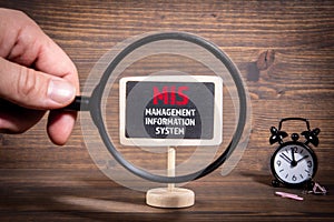 MIS, Management Information System concept. Hand holding magnifying glass