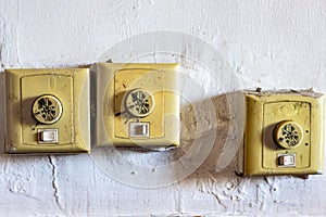 Misaligned old dirty switches for on, off and speed control of ceiling fans against a white wall