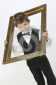 Mischievious boy looks through picture frame