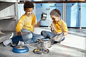 Mischievous little boys creating cacophony by drumming on saucepans