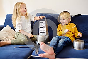 Mischievous preschooler boy and girl play the music using kitchen tools and utensils. Funny small orchestra