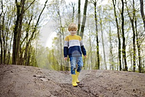 Malizioso bambino in età prescolare logorante la pioggia scarpe secondo fangoso strade. un bambino un divertirsi. al di fuori giochi 