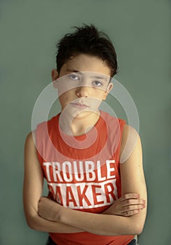 Mischievous teenager boy in trouble maker t-shirt close up sad portrait