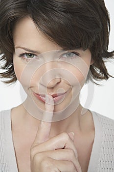 Mischievous Woman Gesturing Silence photo