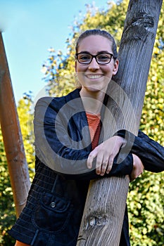 Mischievously smiling young woman clutching a wooden pole