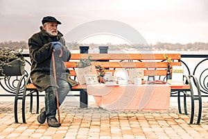 Miserable cold poor man sitting on bench in park