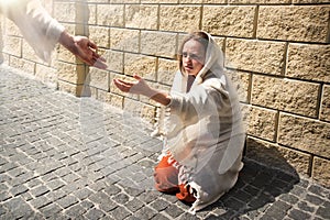 A girl in poor clothes sits on the ground