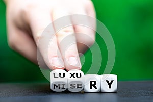 From misery to luxury. Hand turns dice and changes the word misery to luxury photo