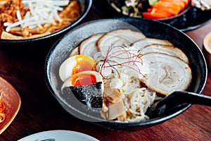 Miso Chashu Ramen: Japanese noodle in Miso soup with chashu pork, boiled egg, dry seaweed and chives in black bowl