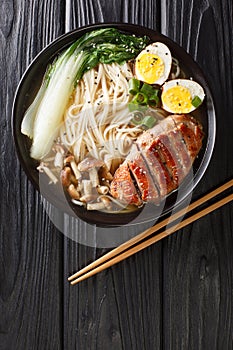 Miso Ramen Asian noodles with egg, duck and pak choi cabbage on dark background closeup. Vertical top view