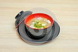 Miso soup with tofu and vegetable in black cup with lid photo