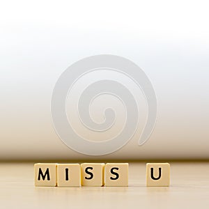 miss you word written in cube on wooden floor on white background